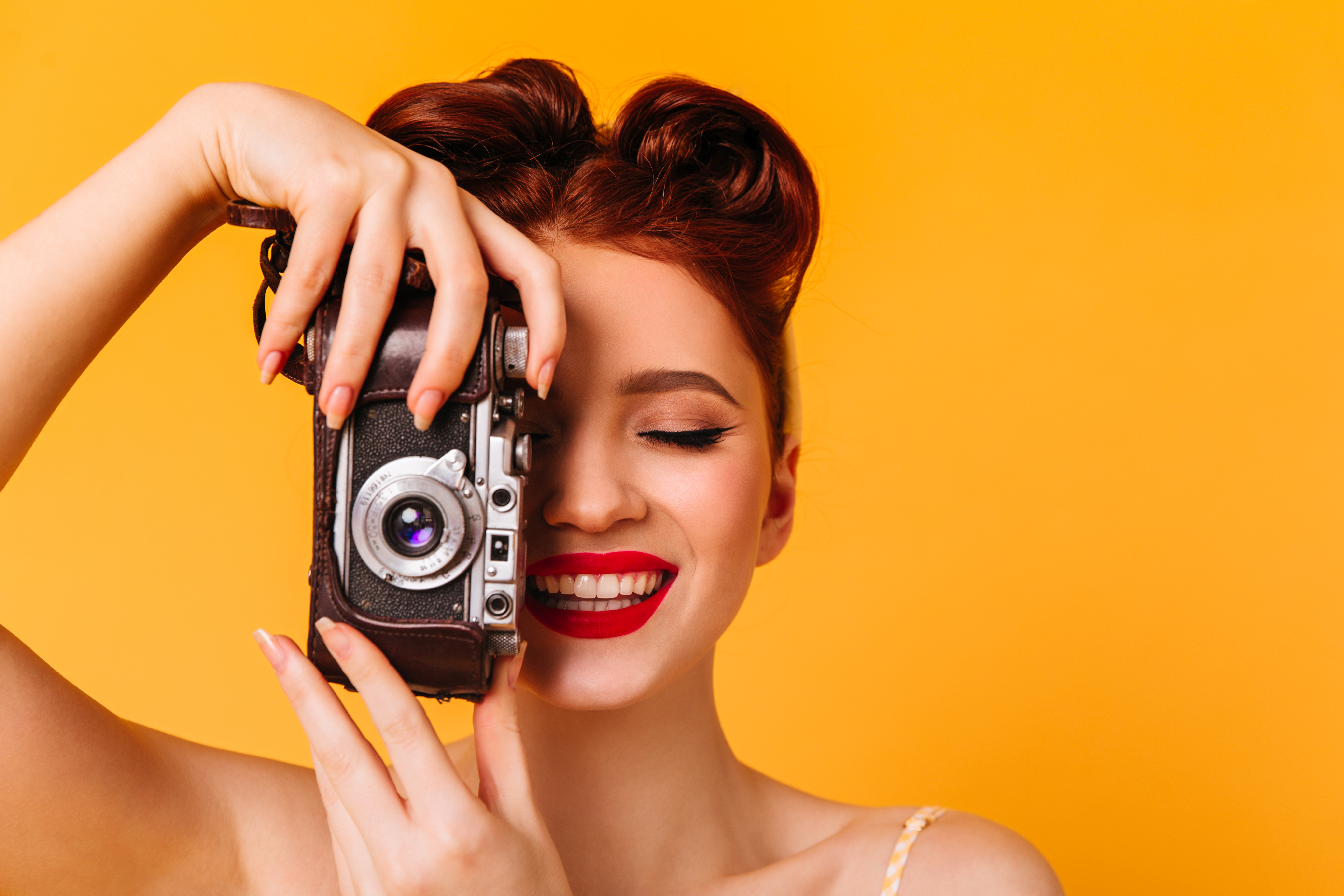 happy-pinup-girl-taking-photos-studio-portrait-woman-with-camera-isolated-yellow-space