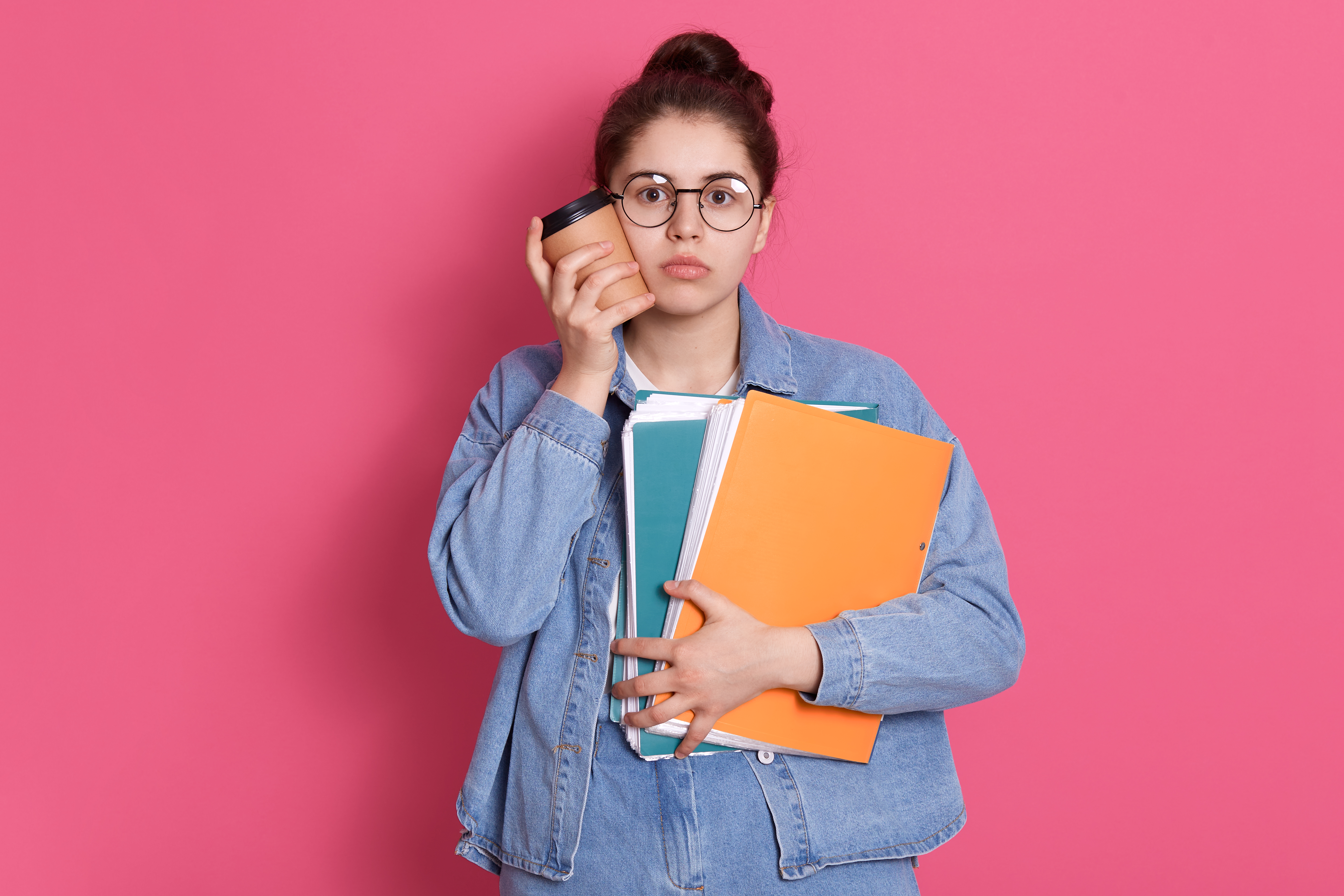 pretty-student-young-woman-touching-her-cheek-with-take-away-coffee-holding-paper-folder